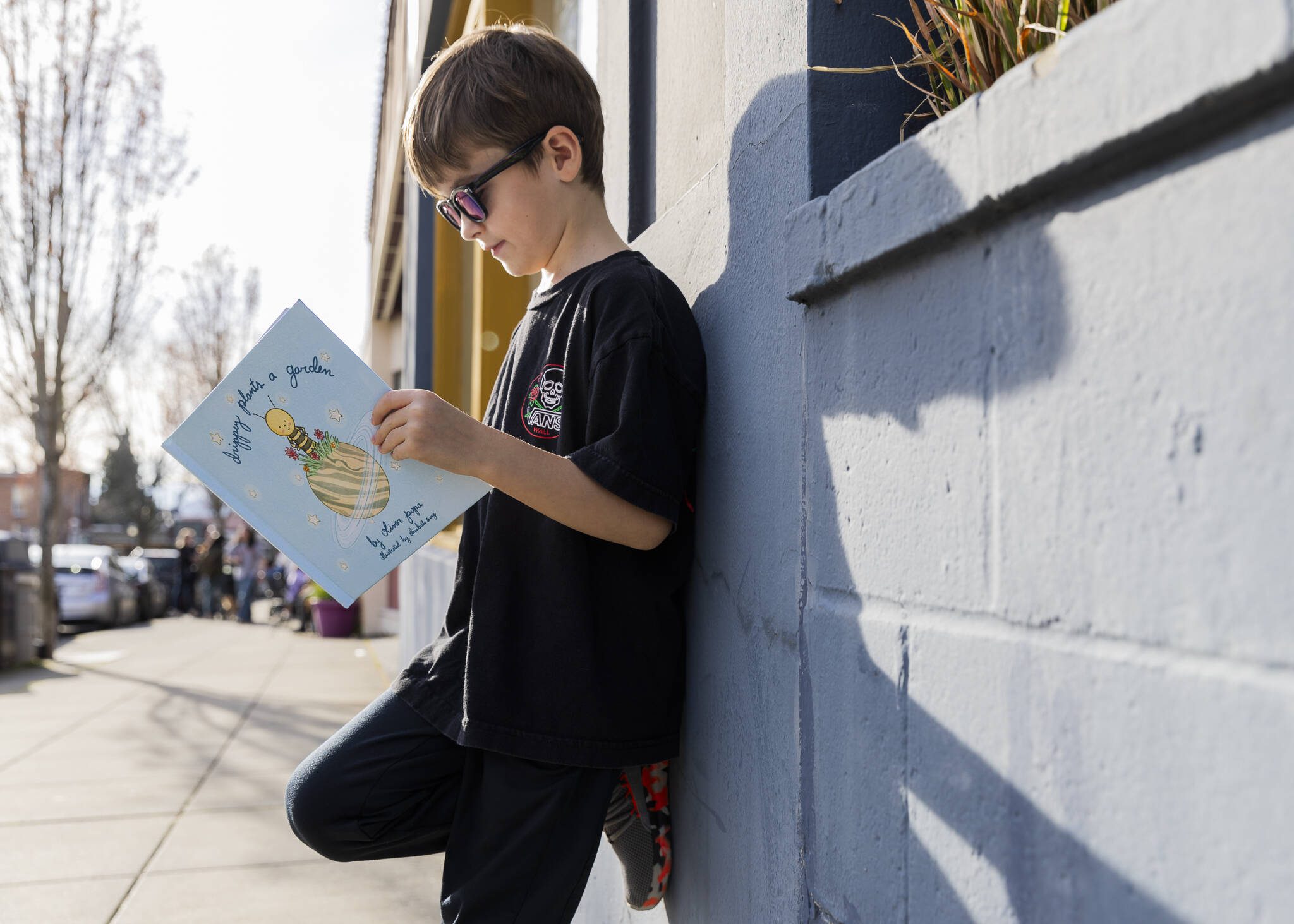 Oliver Popa, 7, poses with his book, “Drippey Plants a Garden,” on Tuesday, March 25, 2025 in Edmonds, Washington. (Olivia Vanni / The Herald)