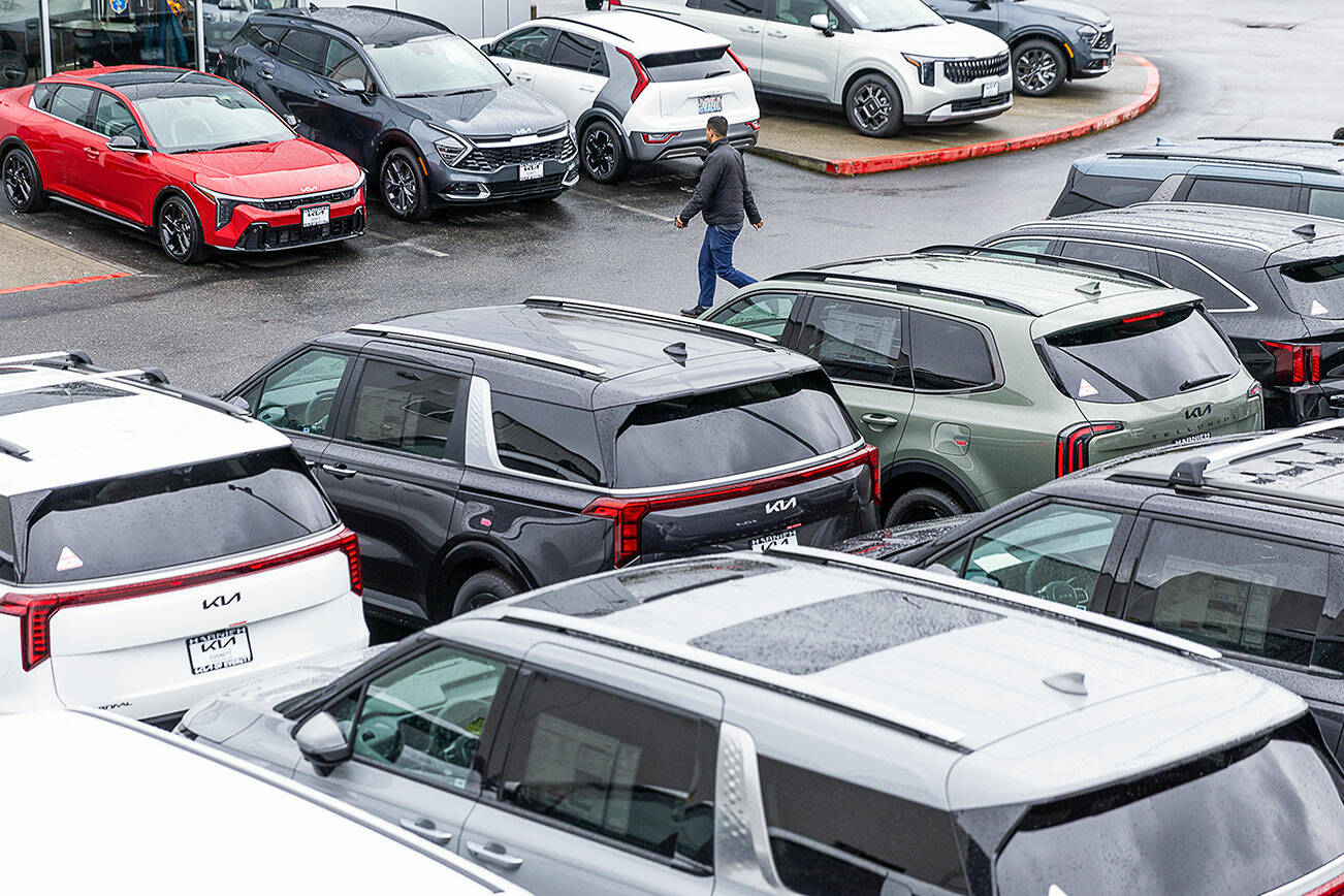 A person walks through the lot at Kia of Everett shopping for a car on Tuesday, April 1, 2025 in Everett, Washington. (Olivia Vanni / The Herald)