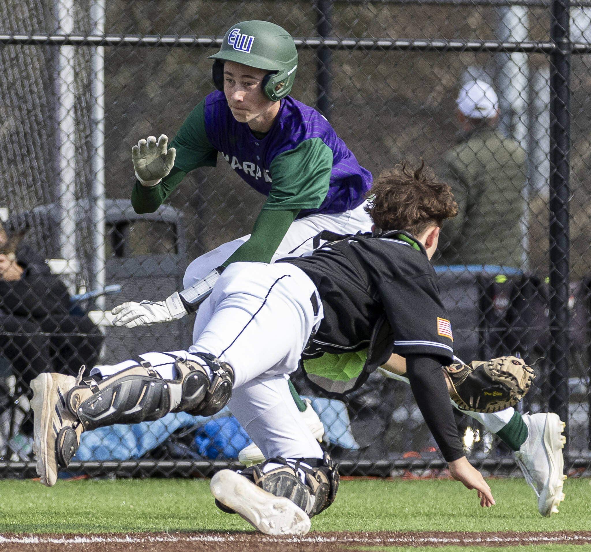 Edmonds-Woodway’s Erik Alsdorf dives around the outstretched glove of Jackson’s Gavin Duckart to score during the game on Wednesday, April 2, 2025 in Edmonds, Washington. (Olivia Vanni / The Herald)