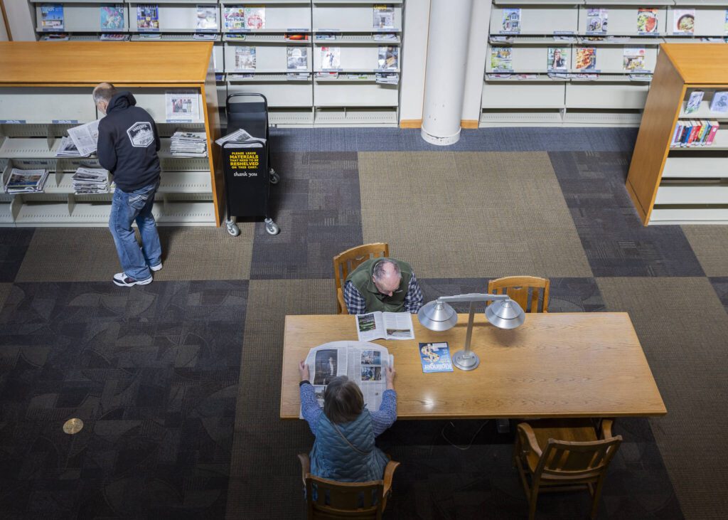 People read newspapers from the library’s selection at the Everett Public Library on Thursday, April 3, 2025, in Everett, Washington. (Olivia Vanni / The Herald)
