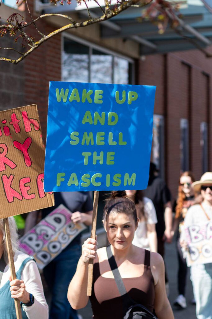 A protester holds her sign while walking down Broadway on Saturday, April 5, 2025, in Everett, Washington. (Aaron Kennedy / The Herald)
