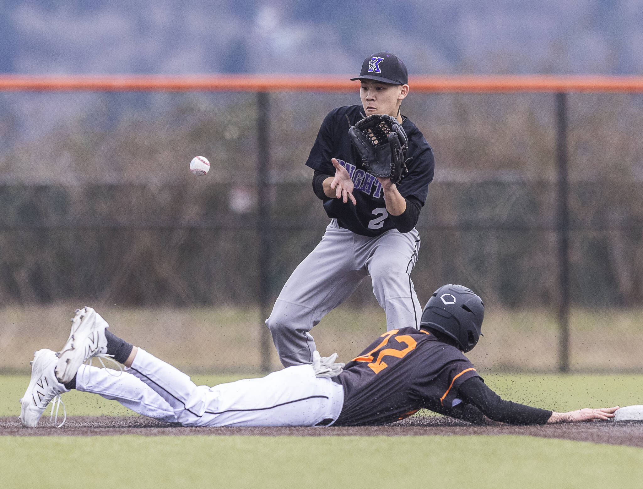 Kamiak’s Colby Koga reaches to catch a throw as Monroe’s Joe Enrico dives back to second base during the game on Friday, March 14, 2025 in Monroe, Washington. (Olivia Vanni / The Herald)