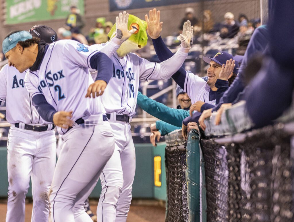 Everett AquaSox outfielder Carson Jones high-fives his teammates in a frog mask after hitting home run during the Opening Day game against the Hillsboro Hops on Tuesday, April 8, 2025 in Everett, Washington. (Olivia Vanni / The Herald)
