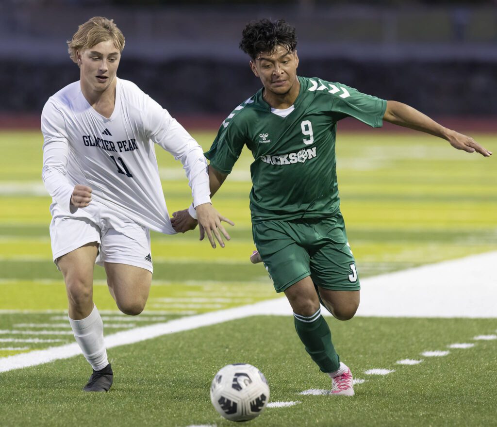 Jackson’s Anthony Gonzales-Marroquin pulls on the jersey of Glacier Peak’s Luke Fullerton as they both run after the ball during the game on Tuesday, April 15, 2025 in Everett, Washington. (Olivia Vanni / The Herald)
