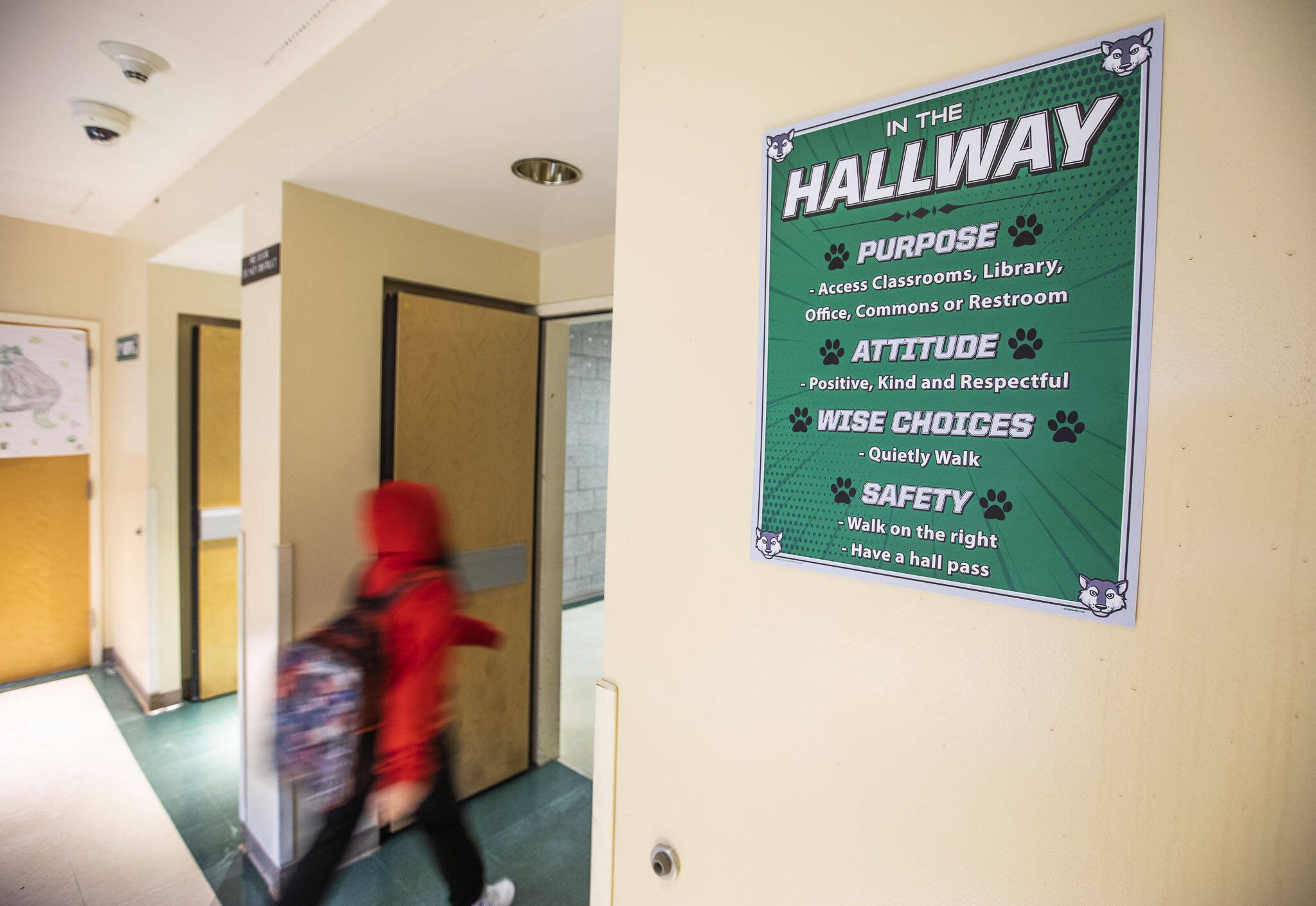 A student walks down a hallway at Evergreen Middle School past a sign displaying different values the students should embody while occupying the space on a 2024 school day in Everett. (Olivia Vanni / The Herald)