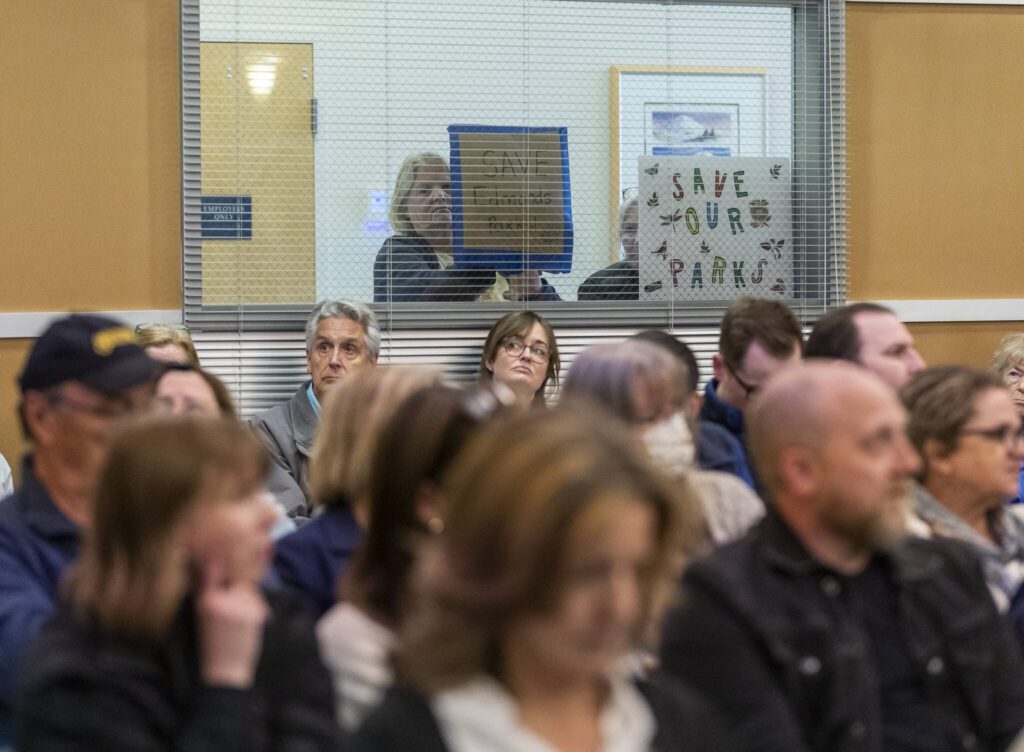 People press signs onto the windows of the city council chambers in protest of the idea of selling Hummingbird Hill Park on Monday, April 21, 2025 in Edmonds, Washington. (Olivia Vanni / The Herald)
