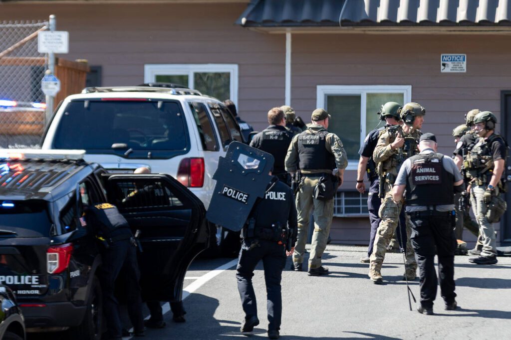 Local law enforcement officers stage in the drive of the Farwest Motel on the 6000 block of Evergreen Way in Everett. Friday, April 18, 2025 (Aaron Kennedy / The Herald)
