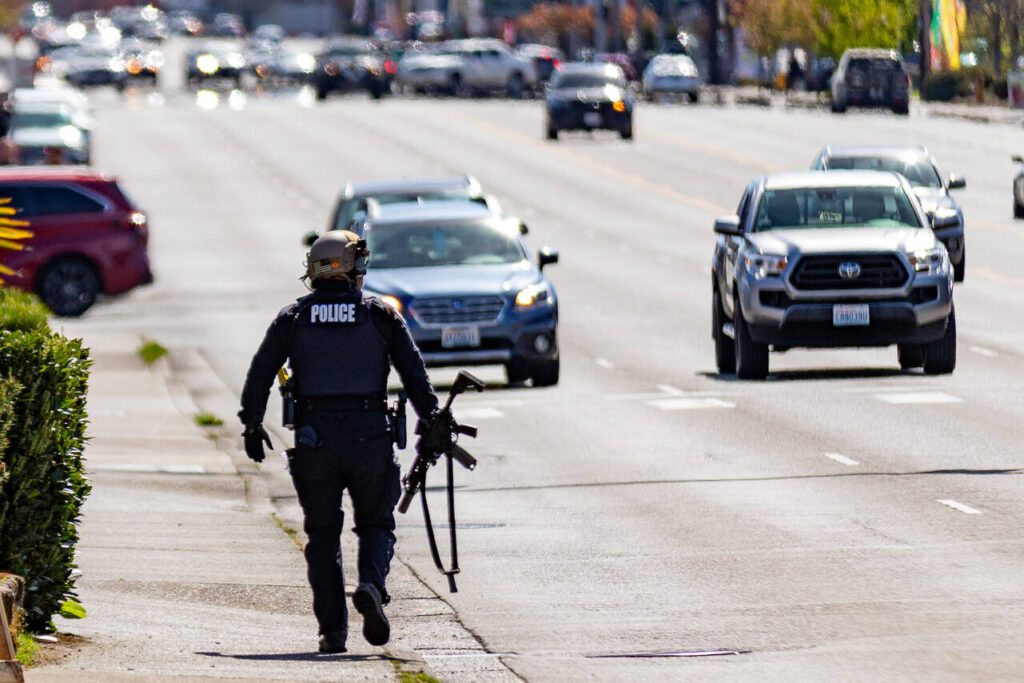 An officer walks down the sidewalk across the street from the Farwest Motel on the 6000 block of Evergreen Way in Everett. Friday, April 18, 2025 (Aaron Kennedy / The Herald)
