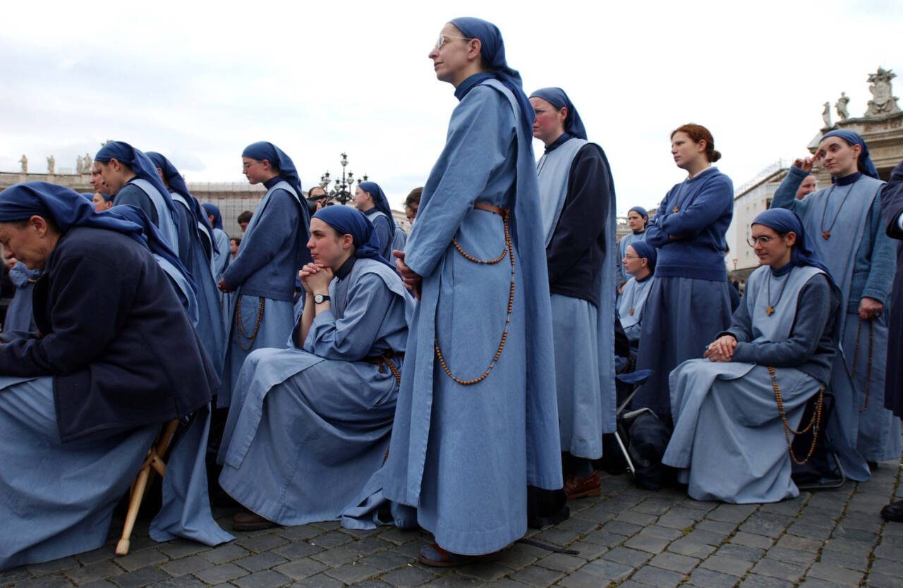 Sisters with the order Lamb of God look in the direction of the chimney over the Sistine Chapel waiting for the telltale smoke to indicate the Cardinals’ election of a new pope, April 19, 2005, in St. Peter’s Square in Vatican City. (James Hill / The New York Times file photo)