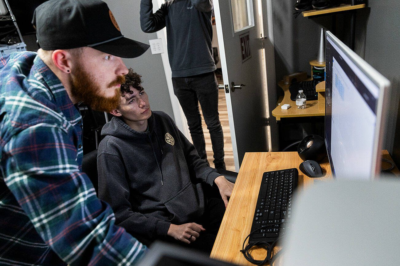 Jonathon DeYonker, left, helps student Dominick Jackson upload documentary footage to Premier at The Teen Storytellers Project on Tuesday, April 29, 2025 in Everett, Washington. (Olivia Vanni / The Herald)