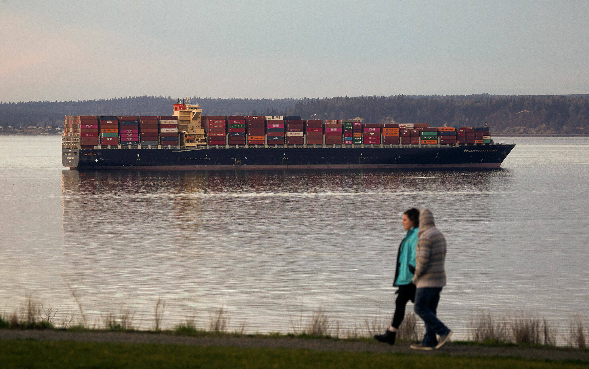 A couple walks around Harborview Park as the Seaspan Brilliance, a 1,105-foot cargo ship, moors near the Port of Everett in 2021. (Andy Bronson / The Herald)