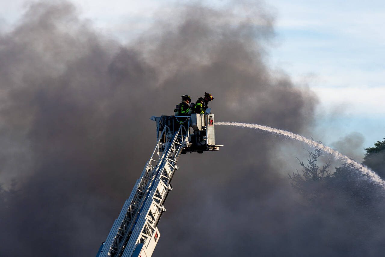 Firefighters spray water from a ladder truck onto a self-storage facility on Monday, May 5, 2025, in Everett, Washington. (Aaron Kennedy / The Herald)