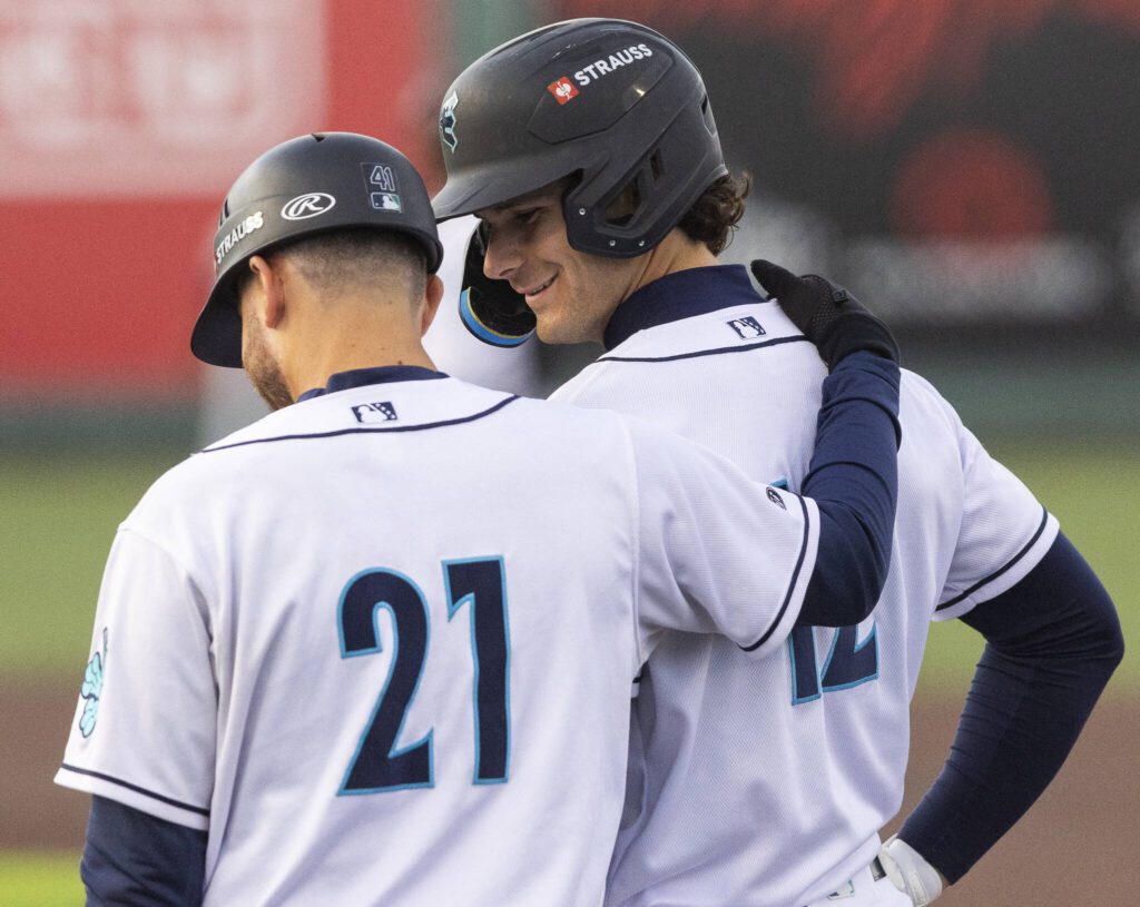 Everett AquaSox infielder Charlie Pagliarini smiles as he talks with bench coach Hecmart Nieves after getting a base hit during the game against the Tri-City Dust Devils on Wednesday, May 7, 2025 in Everett, Washington. (Olivia Vanni / The Herald)
