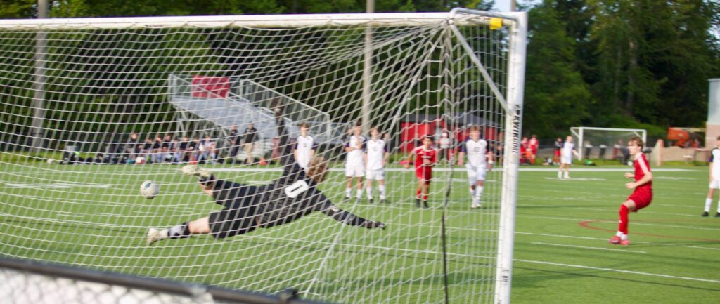 Archbishop Murphy senior Zach Mohr watches his penalty kick hit the back of the net as Anacortes goalkeeper Brian Falen dives in the opposite direction during the Wildcats’ 3-0 win in the District 1 2A Boys Soccer quarterfinals in Everett, Washington on May 8, 2025. (Joe Pohoryles / The Herald)
