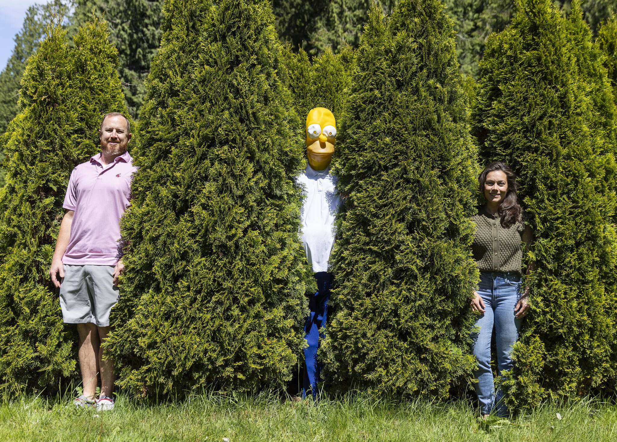 Ryan McMeans, left, and Caitlin Swanson, right, with their “Homer Hedge” meme on West Mukilteo Boulevard in Everett. (Olivia Vanni / The Herald)