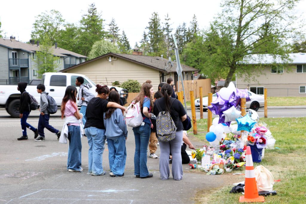 Students from Explorer Middle School gather Wednesday, May 7, 2025, at the site where in south Everett, Washington. Lit candles, flowers, balloons, posters made by students and chalk messages on the pavement were part of a memorial marking the site. (Aspen Anderson / The Herald)
