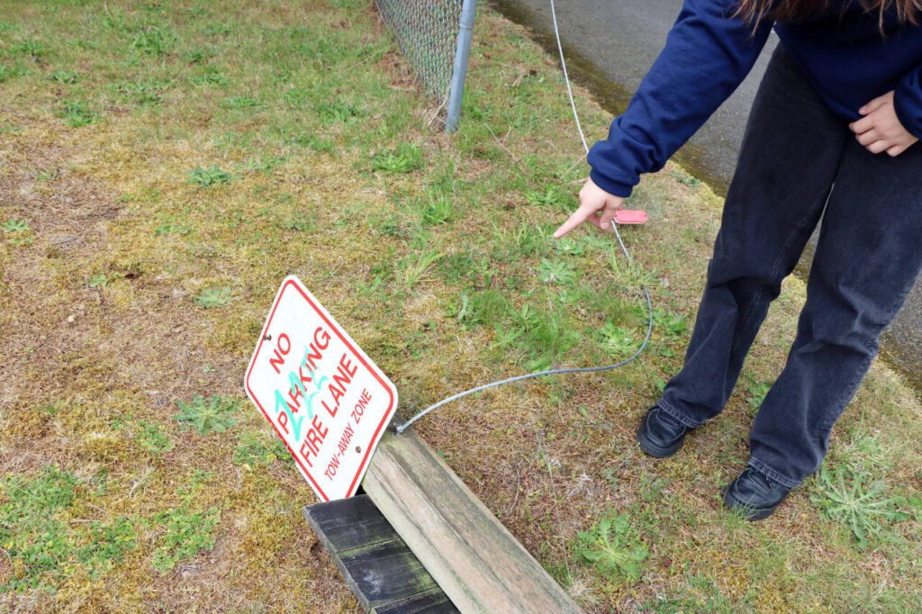 A student points to the remnants of the braided cable that were once connected between a fence post and a traffic bollard on Wednesday, May 7, 2025, in Everett, Washington. (Aspen Anderson / The Herald)
