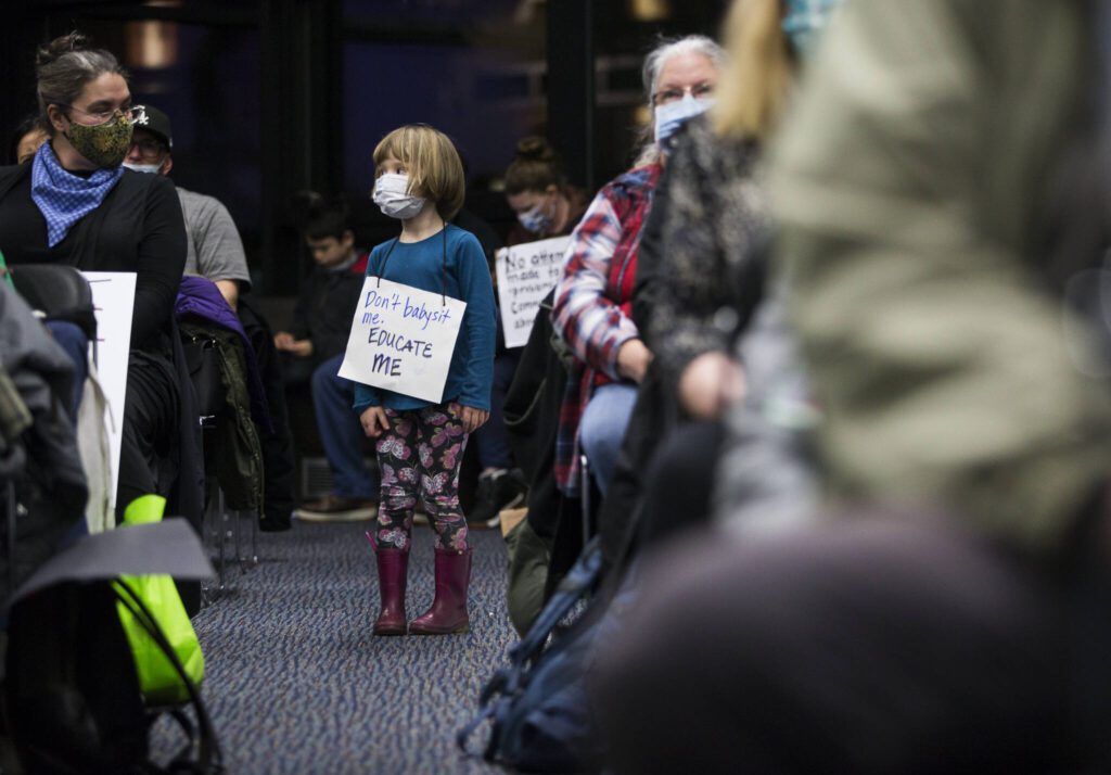 Juniper Player, 4, a student at the Early Learning Center, wears a sign in protest of the proposed plan to close pre-kindergarten facility on Tuesday, Nov. 30, 2021 in Everett, Wa. (Olivia Vanni / The Herald)
