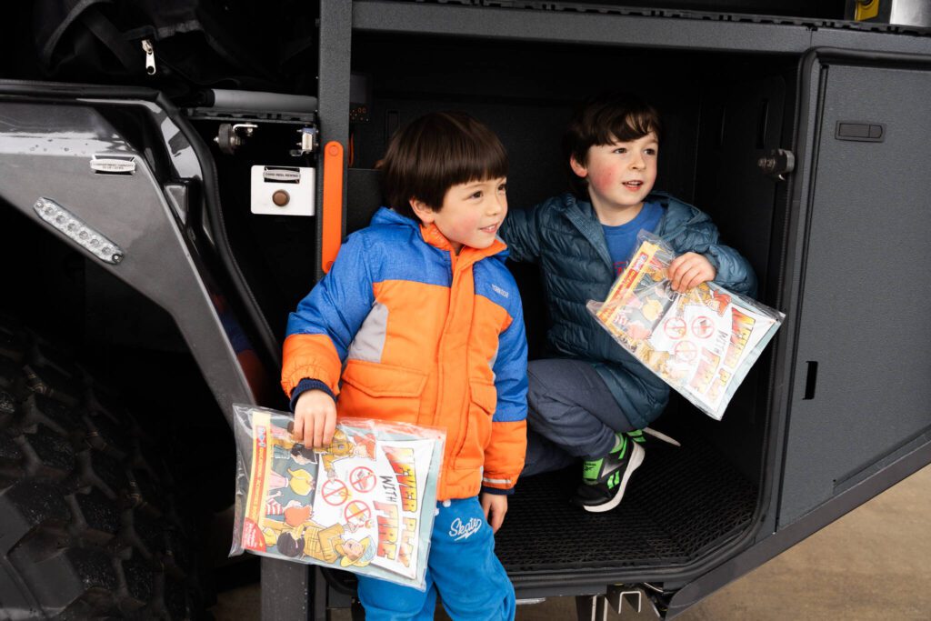 Theodore Lynch, 6, and Aarian Alchholz, 6, sit on the side of a Snohomish County Airport Fire Department fire engine during Paine Field Community Day on Saturday, May 17, 2025, in Everett, Washington. (Will Geschke / The Herald)
