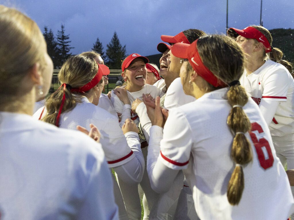 Stanwood’s Olivia Dahl is hugged by her teammates after making a catch in the outfield for the final out to beat Sedro-Woolley in the 3A District 1 Championship on Thursday, May 15, 2025 in Everett, Washington. (Olivia Vanni / The Herald)
