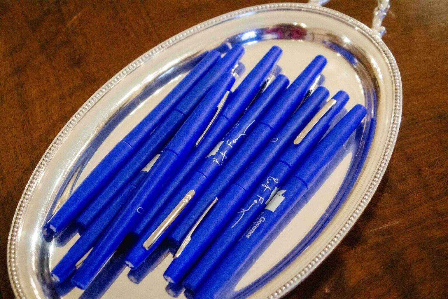 Seen here are the blue pens Gov. Bob Ferguson uses to sign bills. Companies and other interest groups are hoping he’ll opt for red veto ink on a range of tax bills. (Photo by Jacquelyn Jimenez Romero/Washington State Standard)