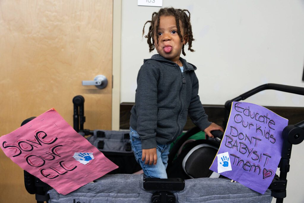 Zakai Richie, 3, who attends the Early Learning Center, sits in a cart with signs protesting the center’s closure on Tuesday, May 20, 2025 in Everett, Washington. (Will Geschke / The Herald)
