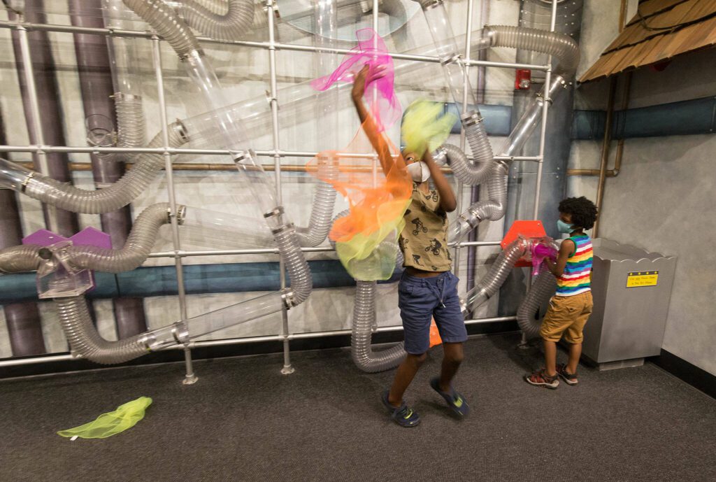 Isaac Nabors, 9, keeps an eye on falling fabric as he and his brother Eli catch scarves that float down in the Air-Mazing Laboratory at Imagine Children’s Museum on Wednesday, June 2, 2021 in Everett, Washington. (Andy Bronson / The Herald)
