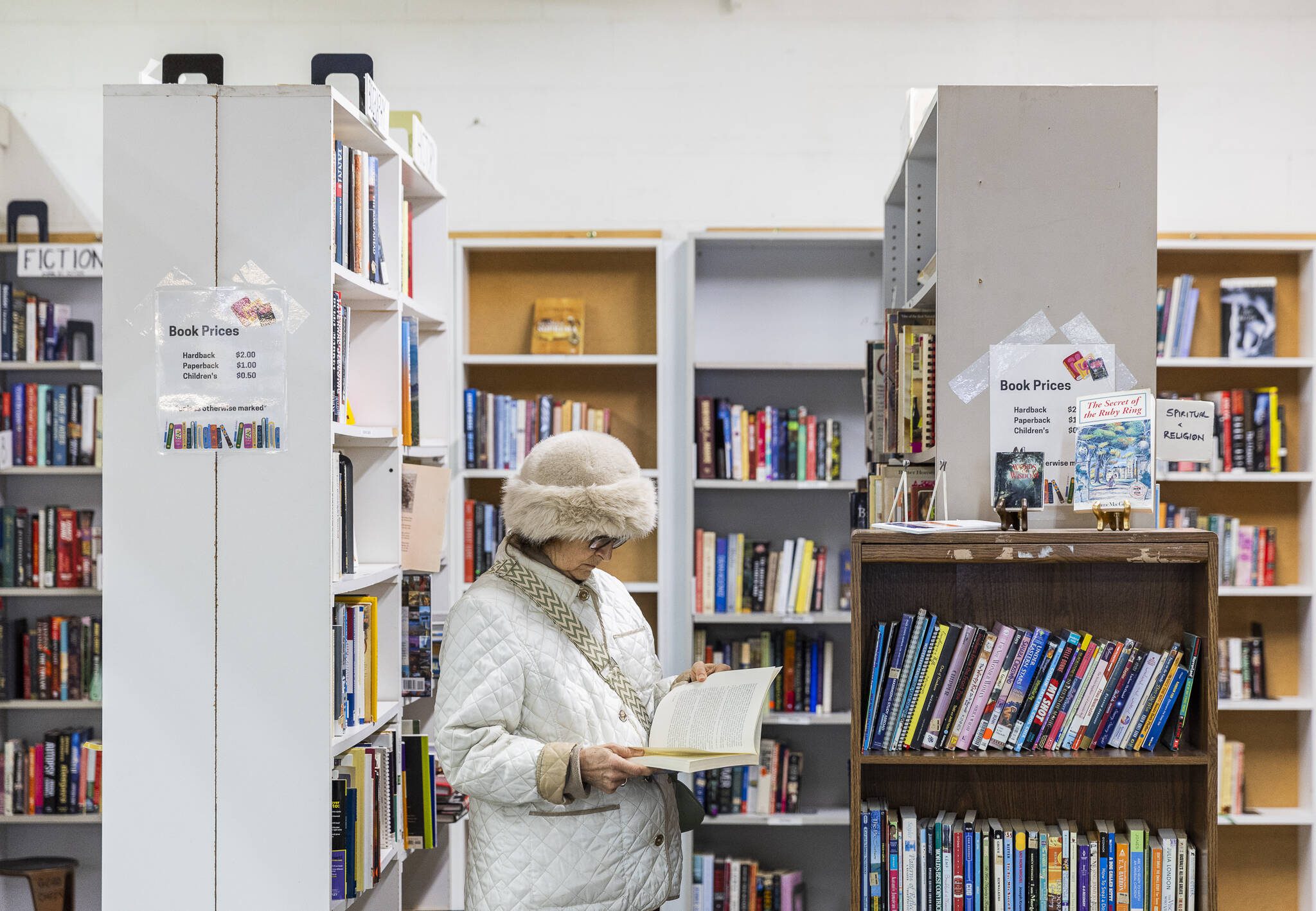 A woman flips through a book at the Good Cheer Thrift Store in Langley. (Olivia Vanni / The Herald)