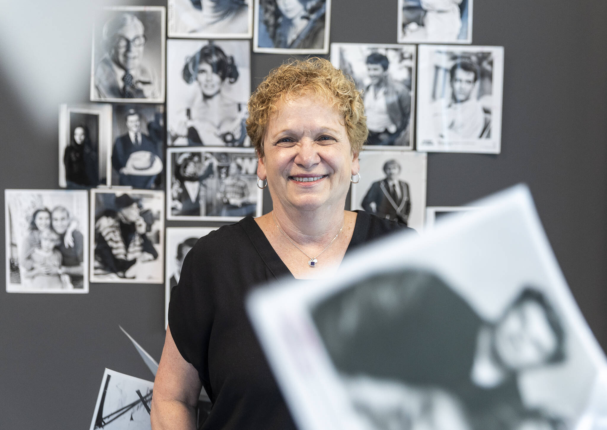 What’s Up With That? columnist Andrea Brown with a selection from hundreds of black-and-white celebrity glossies from The Daily Herald photo vault that she will give away at a pop-up in August. The photos were sent by studios to use for page paste-up in the pre-digital era. (Olivia Vanni / The Herald)