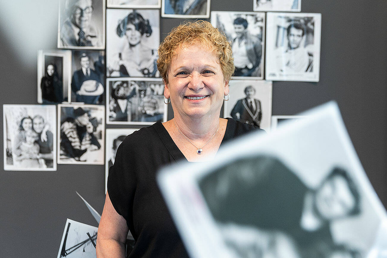 What’s Up columnist Andrea Brown with a selection of black and white glossy promotional photos on Wednesday, June 18, 2025 in Everett, Washington. (Olivia Vanni / The Herald)