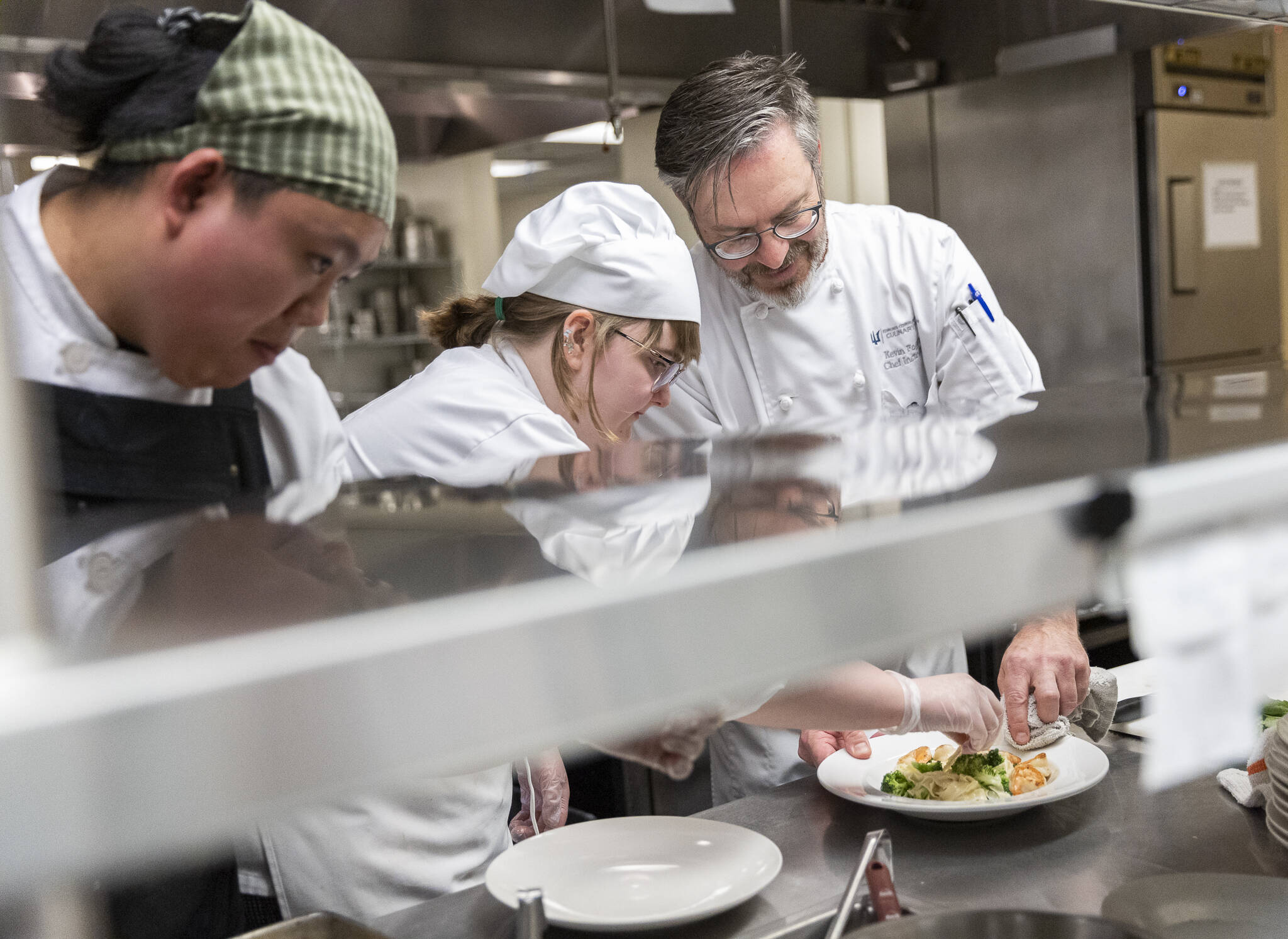 Nathan Tri, left, Natalie Lessley, center, and Chef Instructor Kevin Fogerty plate a fettuccine Alfredo with saute shrimp and broccoli at the Edmonds College Cafe on Thursday, May 29, 2025 in Lynnwood, Washington. (Olivia Vanni / The Herald)