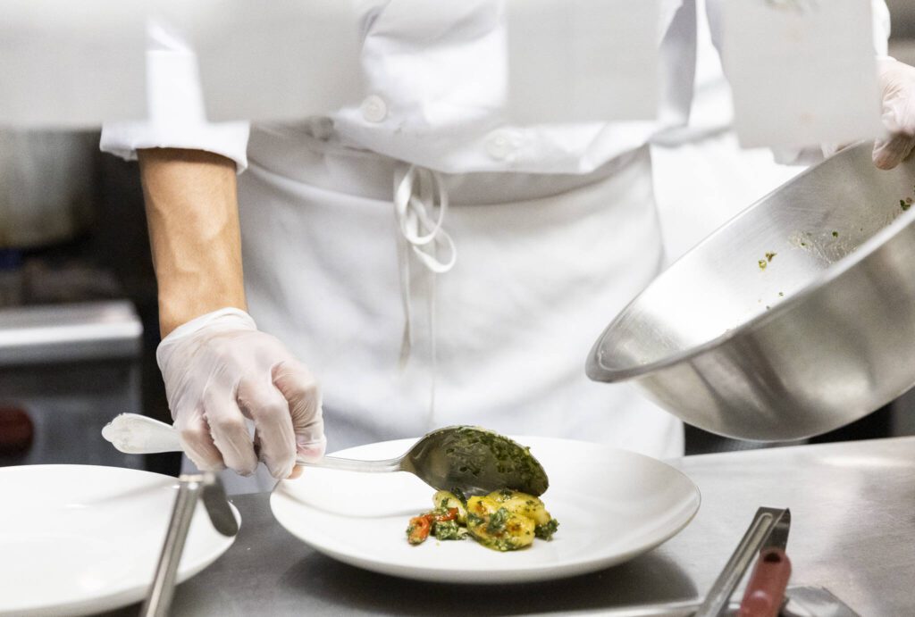 Jahmarion Morey scoops gnocchi tossed in pesto onto a plate to be served at the Edmonds College Cafe on Thursday, May 29, 2025 in Lynnwood, Washington. (Olivia Vanni / The Herald)
