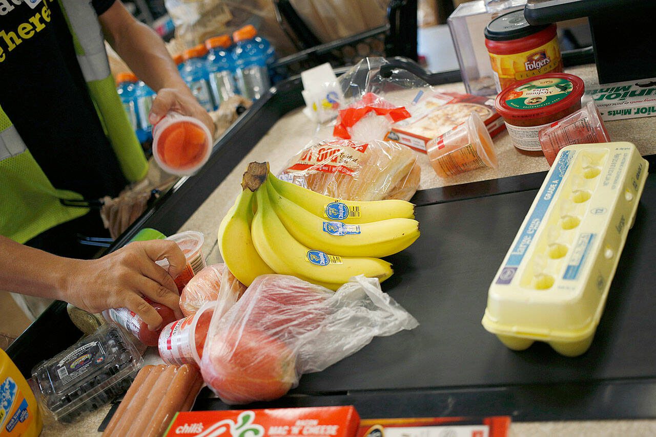 Bloomberg photo by Luke Sharrett
An employee bags groceries for a customer at a checkout counter inside a grocery store in 2017.