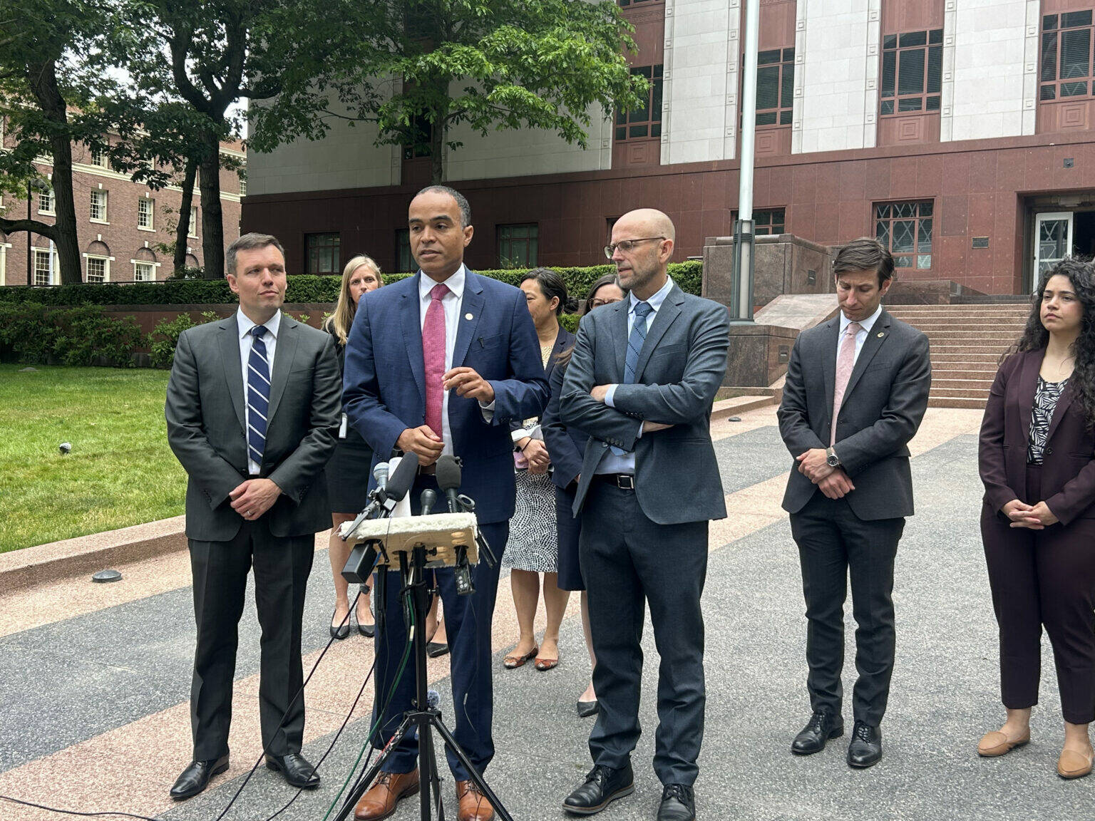 Jake Goldstein-Street / Washington State Standard 
Washington Attorney General Nick Brown, center, speaks to reporters alongside Solicitor General Noah Purcell, left, and Northwest Immigrant Rights Project Legal Director Matt Adams, right, outside a Seattle courthouse where federal appeals court judges heard arguments over President Donald Trump’s executive order on birthright citizenship on Wednesday.