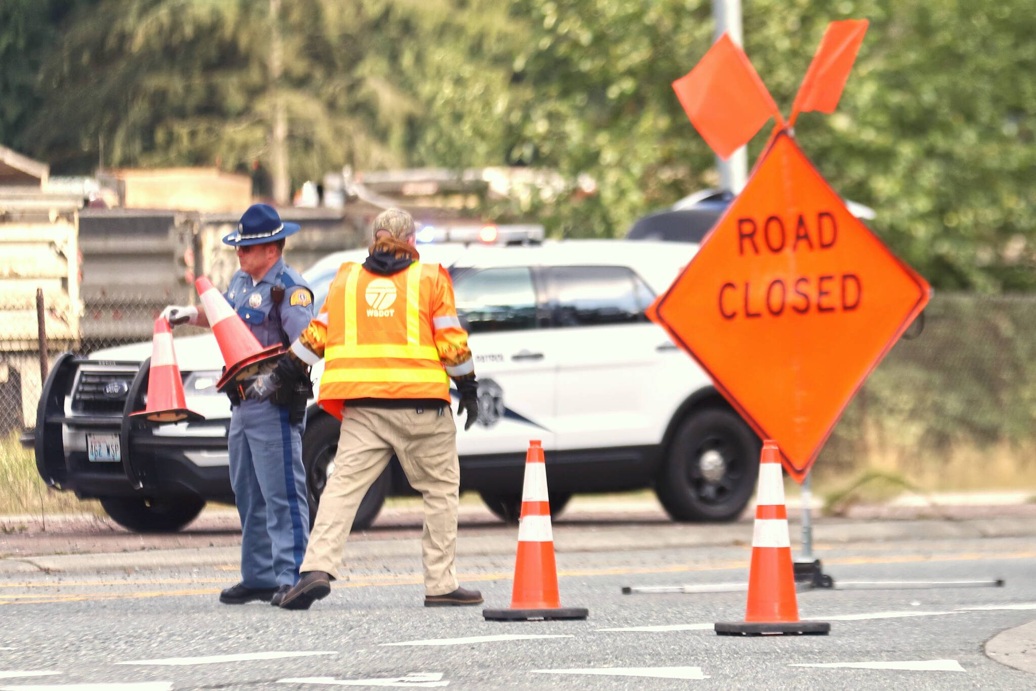 A Washington State trooper and a Washington Department of Transportation employee post signs about a road closure at 84th Street NE and Highway 9 on Sunday. (Michael Henneke / The Herald)