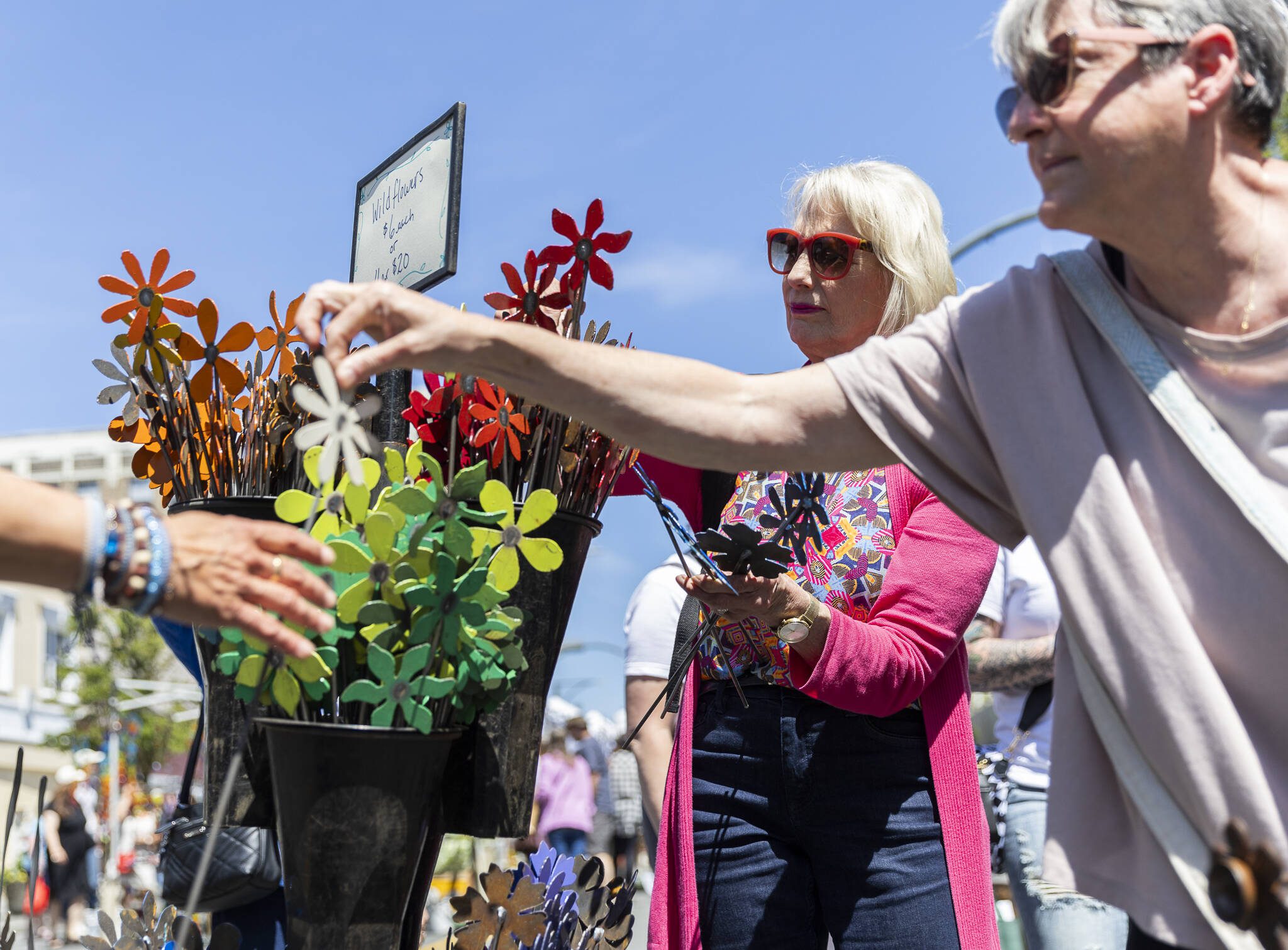 Sue Staple, left, picks out metal flowers while Pamela Davis, right, hands a metal flower to Donna Sisak during Sorticulture on Friday, June 6, 2025 in Everett, Washington. (Olivia Vanni / The Herald)