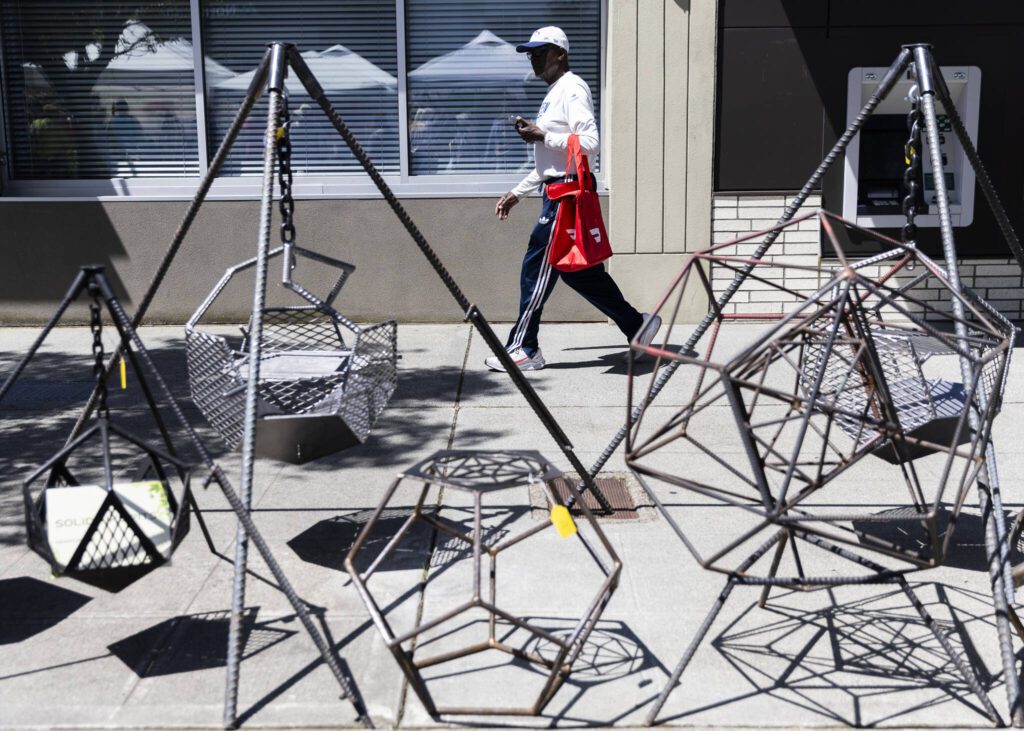 People walk past a selection of metalwork during Sorticulture on Friday, June 6, 2025 in Everett, Washington. (Olivia Vanni / The Herald)
