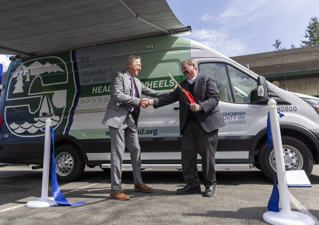 Snohomish County Health Department Director Dennis Worsham and Snohomish County Executive Dave Somers shake hands after cutting the ribbon during the unveiling of the health departments Health on Wheels Van, a mobile public health unit, on Wednesday, April 9, 2025 in Everett, Washington. (Olivia Vanni / The Herald)

