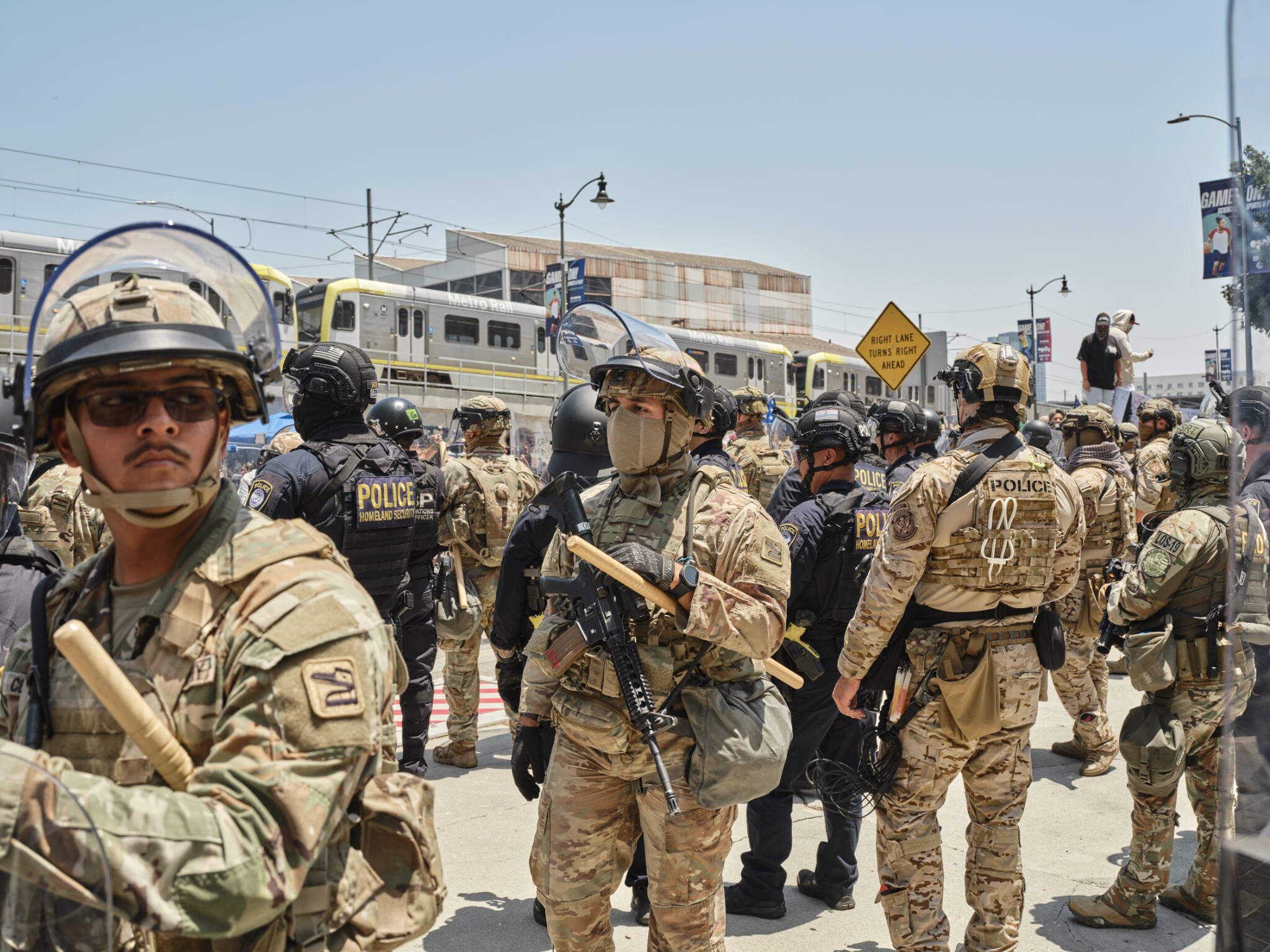 Members of the California National Guard and federal law enforcement stand guard as people protest outside of the Edward R. Roybal Federal Building and Metropolitan Detention Center in Los Angeles, on Tuesday. (Philip Cheung/The New York Times)