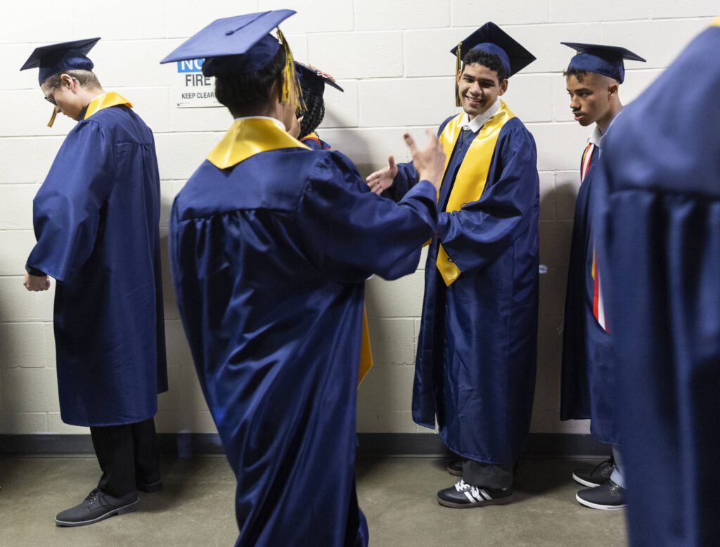 Graduates greet each other as they line up during Mariner High School’s 2025 commencement on Friday, June 13, 2025, at Angel of the Winds Arena in Everett, Washington. (Olivia Vanni / The Herald)
