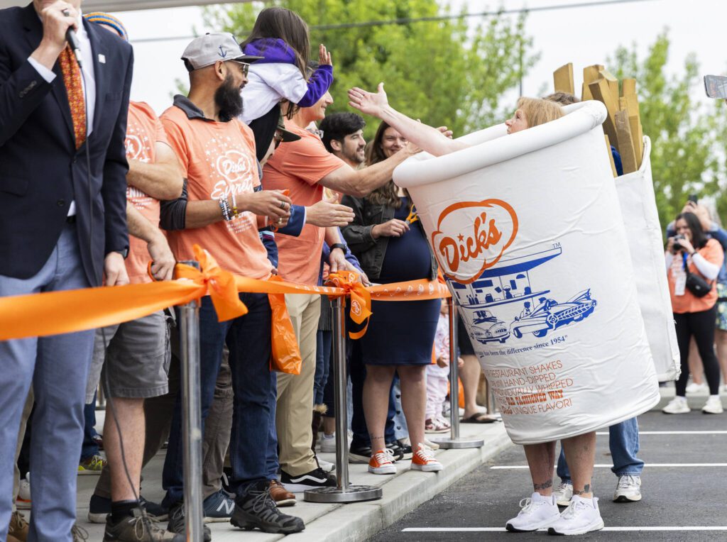 Candie Tallquist high-fives people dressed as a Dick’s Drive-In milkshake on Thursday, June 12, 2025 in Everett, Washington. (Olivia Vanni / The Herald)
