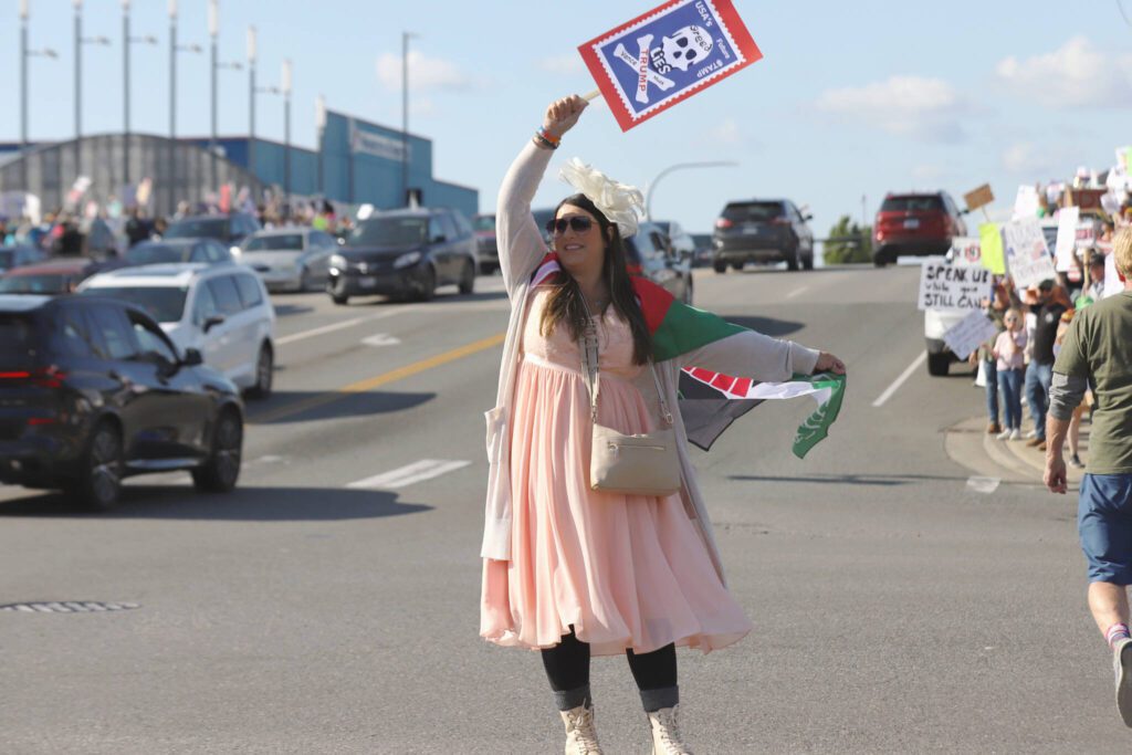 People wave signs during a “No Kings Day” rally along Broadway on Saturday, June 14, 2025, in Everett, Washington. (Mike Henneke / The Herald)

