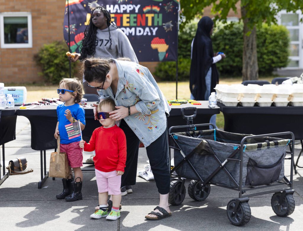 Stephanie W., places sunglasses on her son Louis W., 2, during Lynnwood Juneteenth on Thursday, June 19, 2025 in Lynnwood, Washington. (Olivia Vanni / The Herald)
