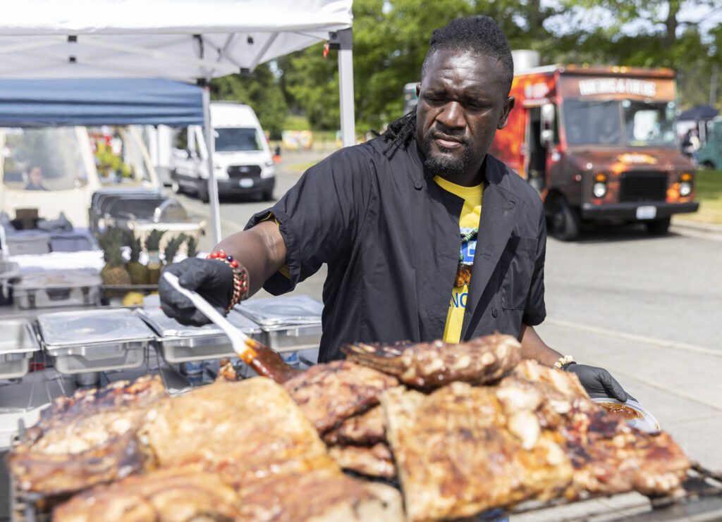 Patrick Pharaoh with Ubuntu Meat Bar & Safari Spice Grill brushes sauce onto pork ribs during Lynnwood Juneteenth on Thursday, June 19, 2025 in Lynnwood, Washington. (Olivia Vanni / The Herald)
