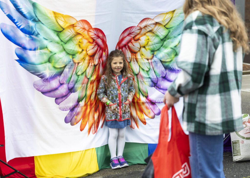 Evelyn Freedman, 5, poses for a picture in front of rainbow wings for her mom Hailey Freedman during the Everett Pride Block Party on Saturday, June 21, 2025 in Everett, Washington. (Olivia Vanni / The Herald)
