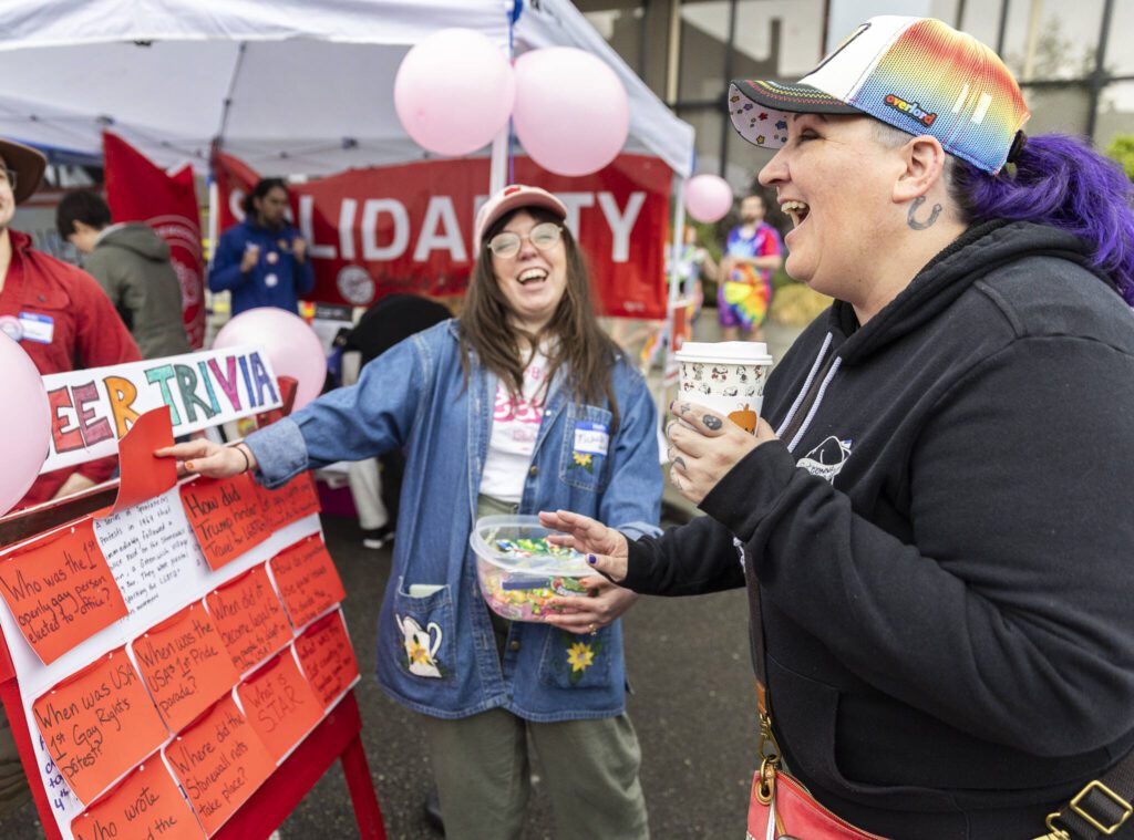 Dana McGlocklin, right, laughs after getting a queer trivia question correct during the Everett Pride Block Party on Saturday, June 21, 2025 in Everett, Washington. (Olivia Vanni / The Herald)
