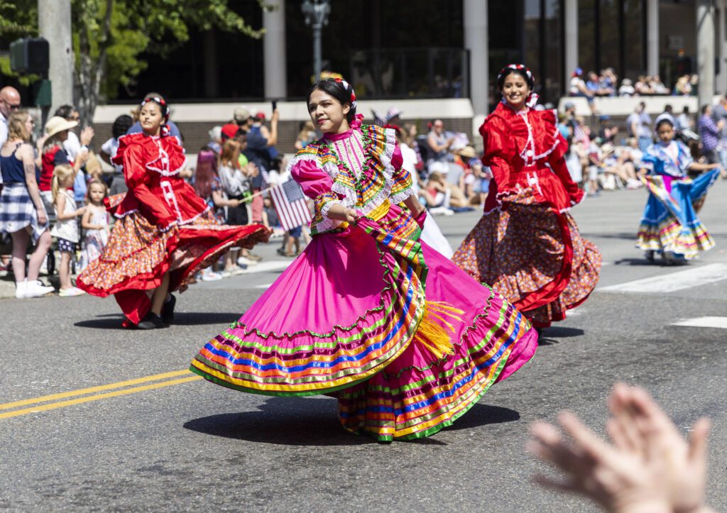Baile folklórico dancers make their way down Colby Avenue as people clap during the Fourth of July parade on Friday, July 4, 2025 in Everett, Washington. (Olivia Vanni / The Herald)
