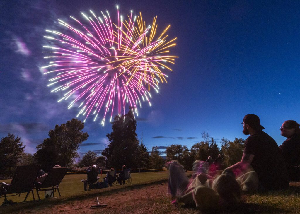 People watch fireworks over Lake Ballinger from Nile Shrine Golf Course on Thursday, July 3, 2025 in Mountlake Terrace, Washington. (Olivia Vanni / The Herald)
