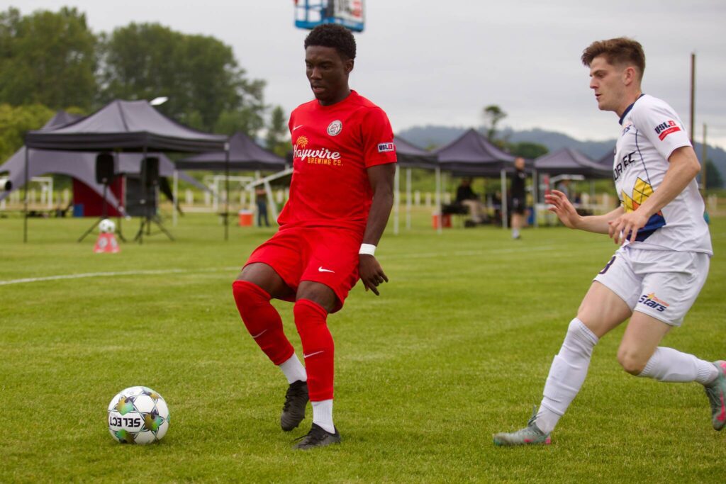 Midfielder Clarens Dollin fends off a Stars defender during Snohomish United’s 5-1 win against Tacoma at Stockers Fields on July 9, 2025 (Joe Pohoryles / The Herald)
