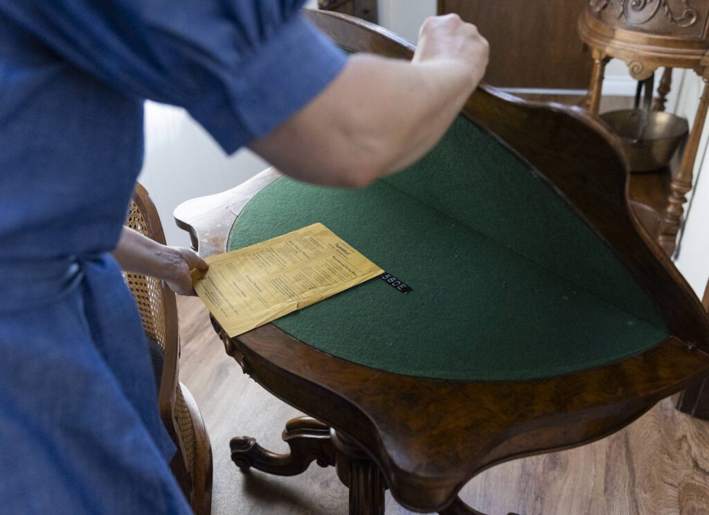 Annzolee Olsen shows the auction notes from her father with the poker table that was featured in a Robert Redford movie. (Olivia Vanni / The Herald)

